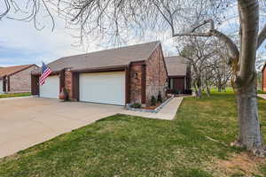 View of front of house with roof with shingles, an attached garage, driveway, brick siding, and a front yard