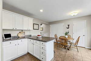 Kitchen featuring dark countertops, a peninsula, white cabinetry, dark tile patterned floors, and recessed lighting