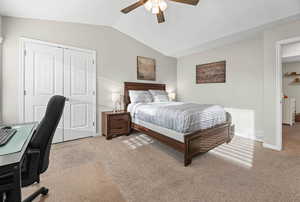 Bedroom with light colored carpet, a desk, vaulted ceiling, a closet, and ceiling fan