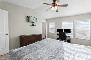 Bedroom with vaulted ceiling, a desk, ceiling fan, and carpet floors