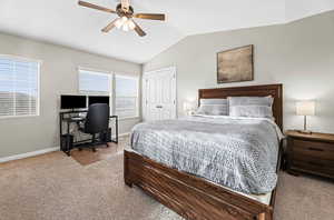 Bedroom featuring light carpet, a closet, lofted ceiling, a desk, and a ceiling fan