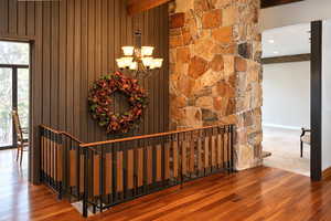Stairs with a chandelier, wood-type flooring, and beamed ceiling