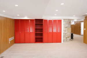 Unfurnished bedroom with wood walls, light colored carpet, multiple closets, and recessed lighting