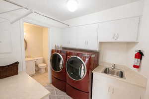 Laundry area featuring washer and clothes dryer, light tile patterned flooring, and electric panel