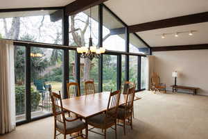 Carpeted dining space with floor to ceiling windows and a chandelier