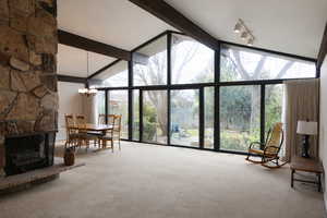 Living area with floor to ceiling windows, light colored carpet, a fireplace, and hanging lights