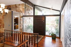 Foyer with wood finished floors, lofted ceiling with beams, and suspended lighting