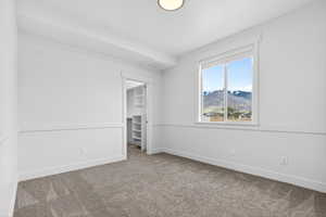 Unfurnished bedroom featuring a walk in closet, carpet, and a mountain view