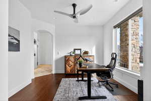 Office space with ceiling fan, arched walkways, dark wood-type flooring, and recessed lighting