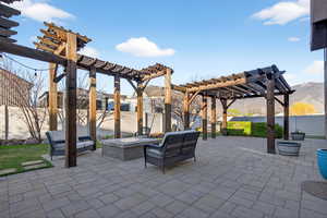 Fenced backyard featuring a pergola, a patio area, a mountain view, and an outdoor living space with a fire pit