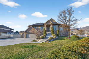 Craftsman-style home featuring stone siding, roof mounted solar panels, a garage, driveway, and a mountain view