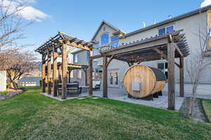 Rear view of house featuring a pergola, a patio area, an outdoor hangout area, a lawn, and stucco siding
