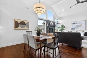 Dining area featuring a fireplace, vaulted ceiling, dark wood-style flooring, ceiling fan, and recessed lighting