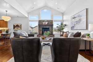 Living area with hardwood / wood-style floors, a fireplace, plenty of natural light, a high ceiling, and recessed lighting