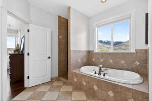 Bathroom featuring a garden tub, walk in shower, and light tile patterned floors