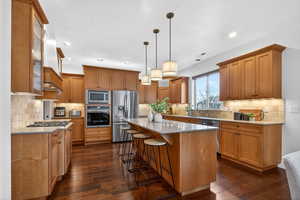Kitchen with light stone counters, a kitchen bar, stainless steel appliances, and a kitchen island