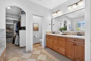 Bathroom with double vanity, a walk in closet, and light tile patterned flooring