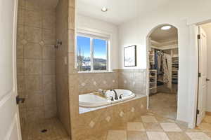 Bathroom with a bath, a shower stall, a spacious closet, light tile patterned flooring, and recessed lighting