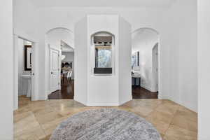 Corridor featuring light tile patterned floors and arched walkways