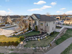 View of front of house with stone siding, a residential view, roof mounted solar panels, and stucco siding