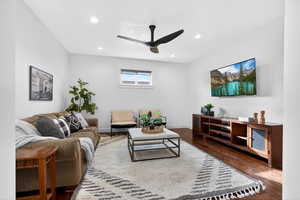 Living room with ceiling fan, dark wood-type flooring, and recessed lighting