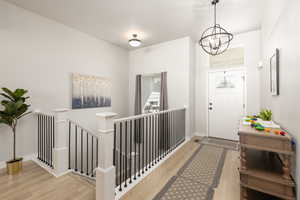 Foyer entrance with light wood finished floors and a chandelier