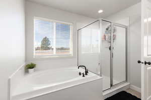 Full bathroom featuring a shower stall, a bath, and recessed lighting