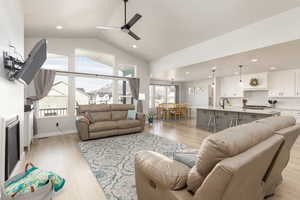 Living area with a ceiling fan, light wood-style flooring, a high ceiling, and recessed lighting