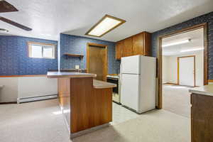 Kitchen featuring white appliances, wood finish cabinets, a textured ceiling, open shelves, and a baseboard radiator