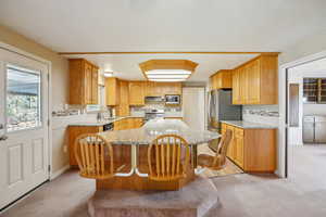 Kitchen with light stone counters, stainless steel appliances, plenty of natural light, and a breakfast bar