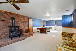 Recreation room featuring billiards, carpet, wallpapered walls, a wood stove, and a textured ceiling