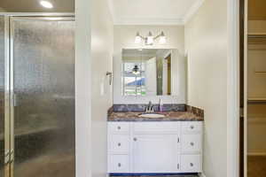 Full bath featuring vanity, crown molding, a spacious closet, and a shower stall