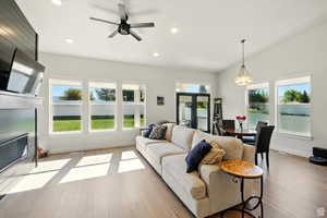 Living room featuring a fireplace with flush hearth, wood finished floors, recessed lighting, ceiling fan, and French patio doors that one into dining room