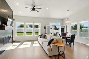 Living room featuring a fireplace with flush hearth, wood finished floors, recessed lighting, ceiling fan, and French patio doors that one into dining room