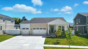 View of front of house featuring board and batten siding,  attached oversized 3-car garage, stone siding, concrete driveway, and covered porch