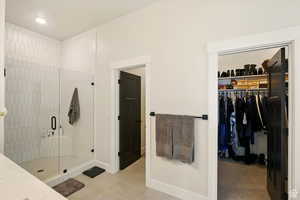 Large primary bathroom with a shower stall, tile patterned floors, a walk-in closet