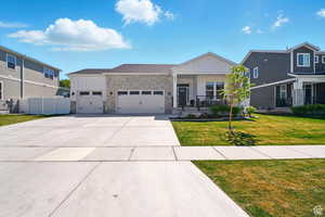 View of front of home featuring a garage, stone siding, concrete driveway, and covered porch