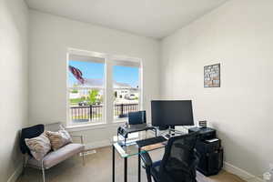 Carpeted home office space with large windows and blinds