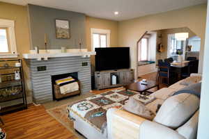Living area with wood finished floors, arched walkways, and a brick fireplace
