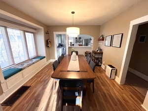 Dining room featuring wood finished floors, a textured ceiling, and arched walkways