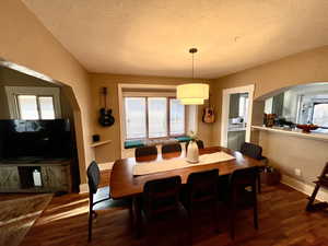 Dining room with arched walkways, wood finished floors, and a textured ceiling