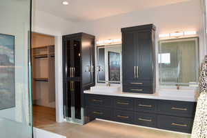 Full bathroom with double vanity, a walk in closet, a shower, and recessed lighting