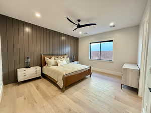 Bedroom featuring wood walls, light wood-style floors, an accent wall, a ceiling fan, and recessed lighting