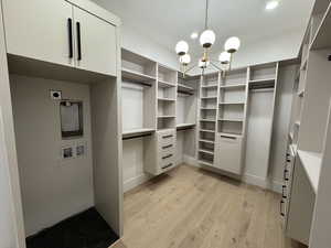 Walk in closet with a chandelier and light wood-style floors