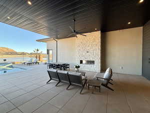View of patio / terrace with ceiling fan, an outdoor stone fireplace, an outdoor pool, and outdoor dining area