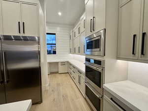 Kitchen with built in appliances, light wood-type flooring, light stone counters, and recessed lighting