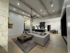 Living area with a chandelier, light wood finished floors, and beam ceiling