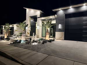 Exterior entry at twilight with stone siding, a garage, and driveway