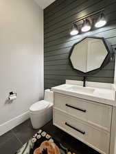 Bathroom featuring wooden walls, vanity, and dark tile patterned floors