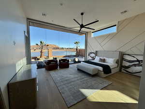 Bedroom featuring expansive windows, hardwood / wood-style floors, and a ceiling fan